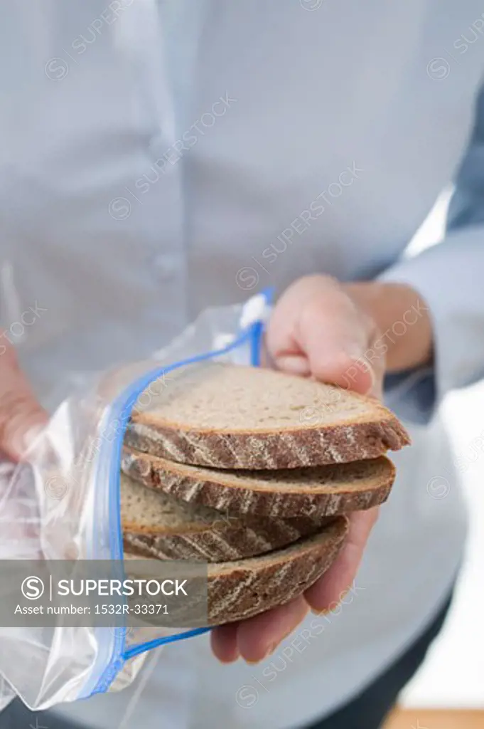 Woman holding slices of bread in a plastic zipper bag