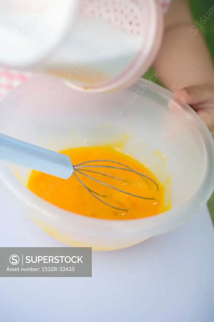 Child whisking egg yolks