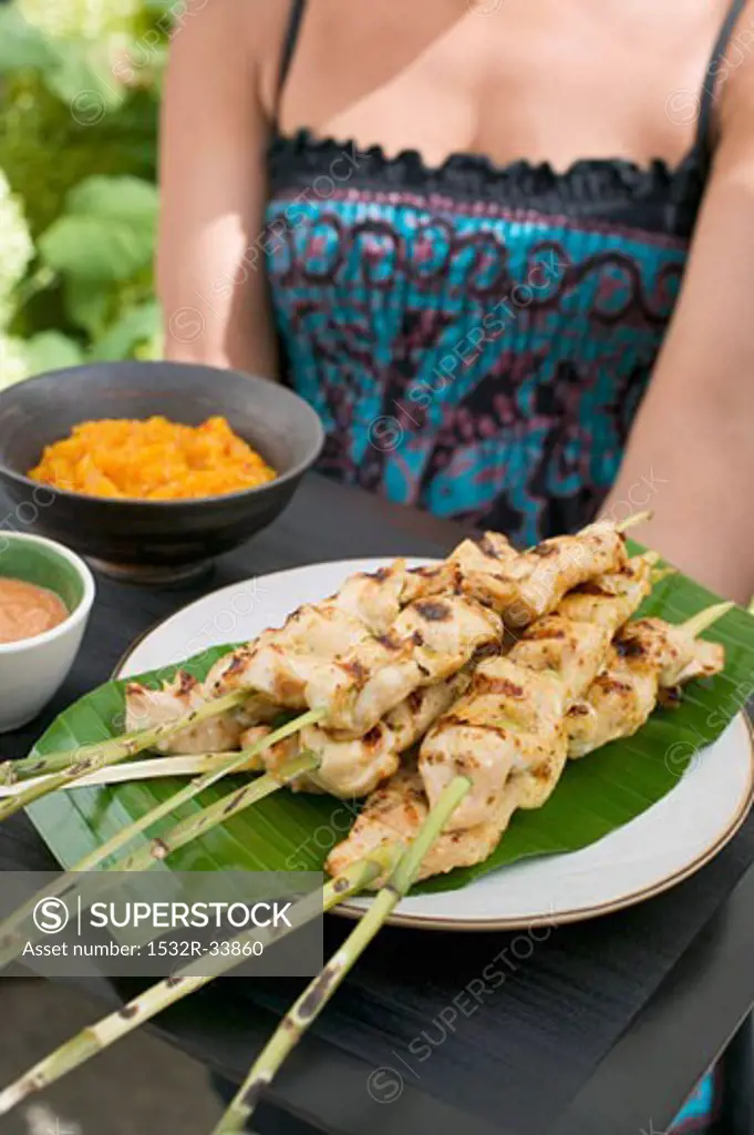 Woman holding tray of satay and dips