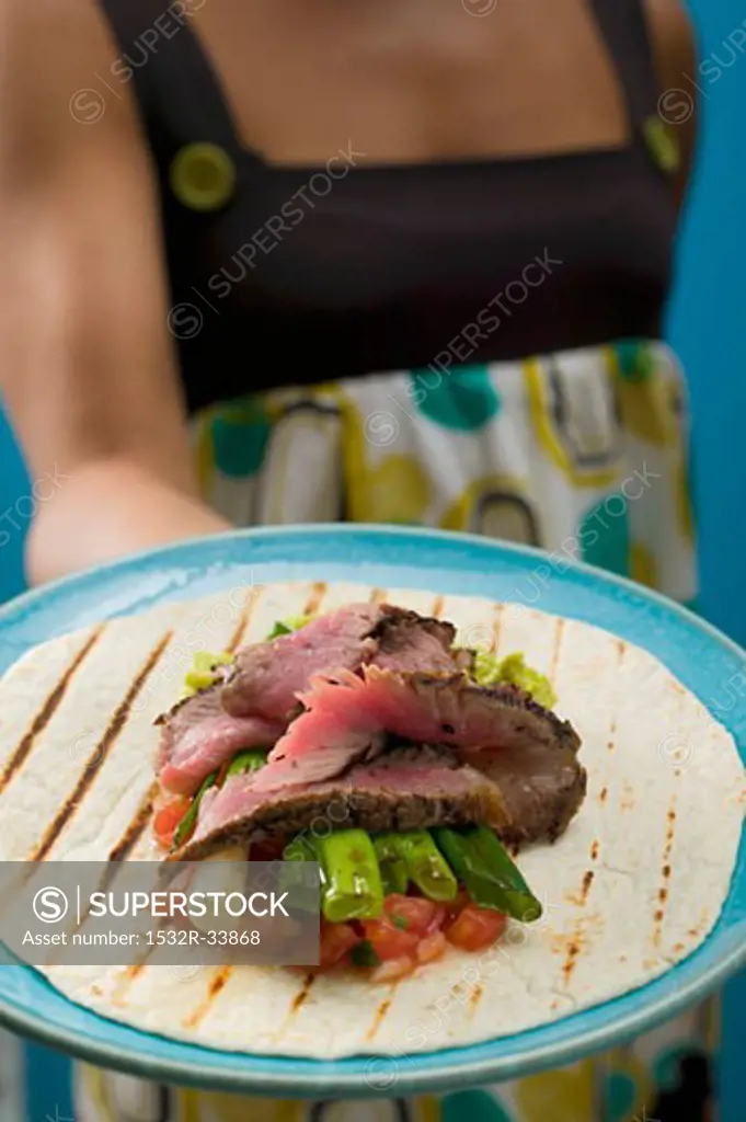 Woman serving tortilla with meat and vegetables