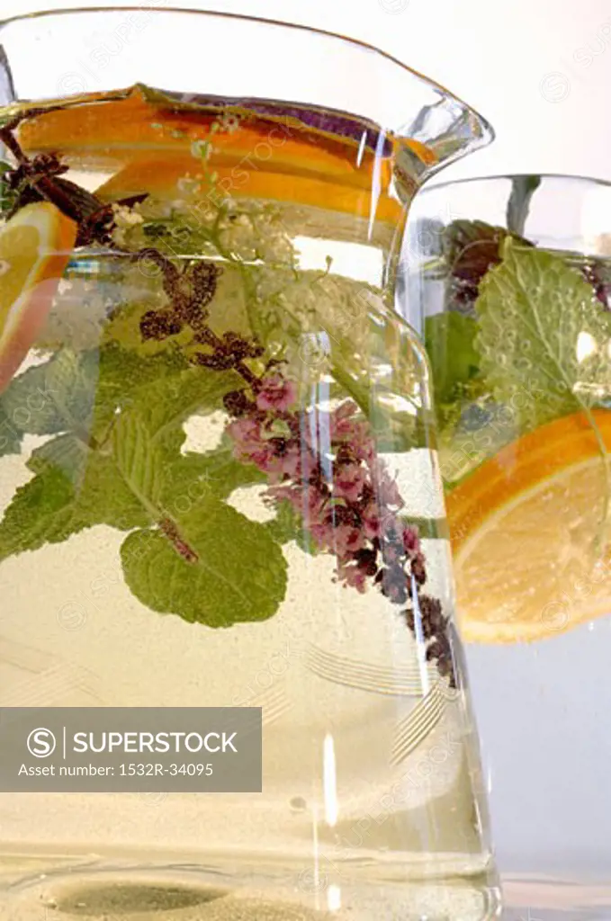 Herbal drink with slices of lemon in glass jug