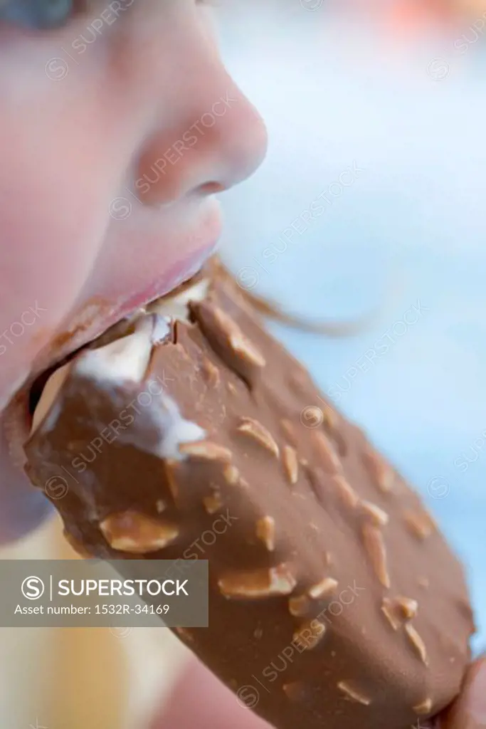 Small girl eating an ice cream on a stick (close-up)