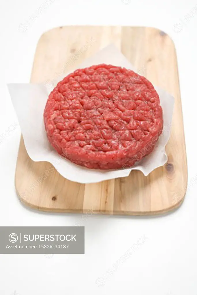 Raw burger on paper on chopping board