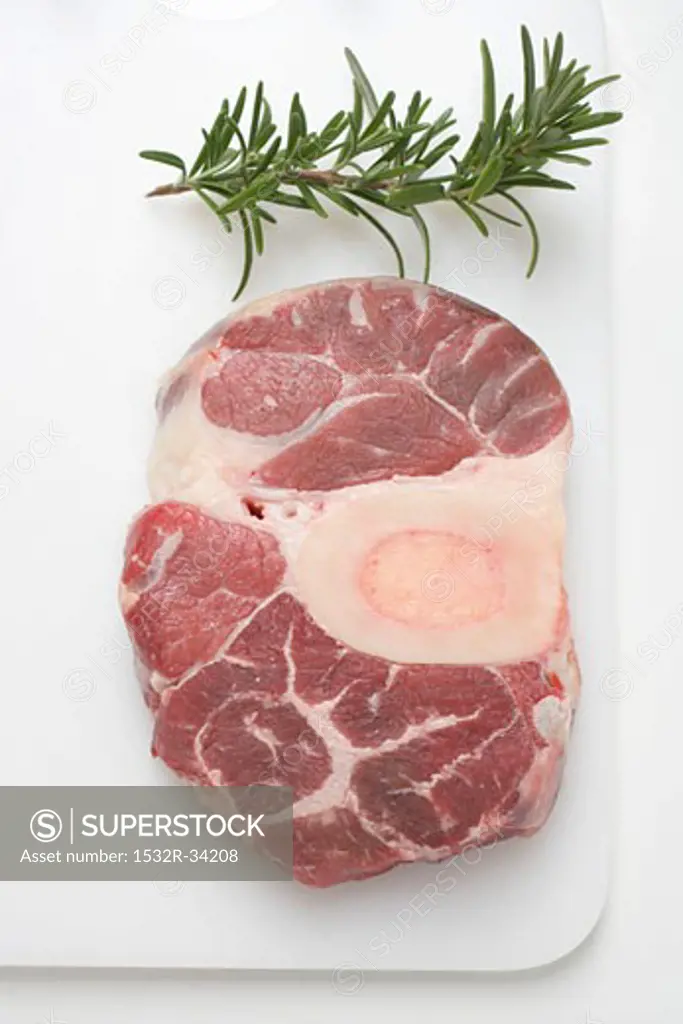 Slice of beef from the leg on chopping board, sprig of rosemary