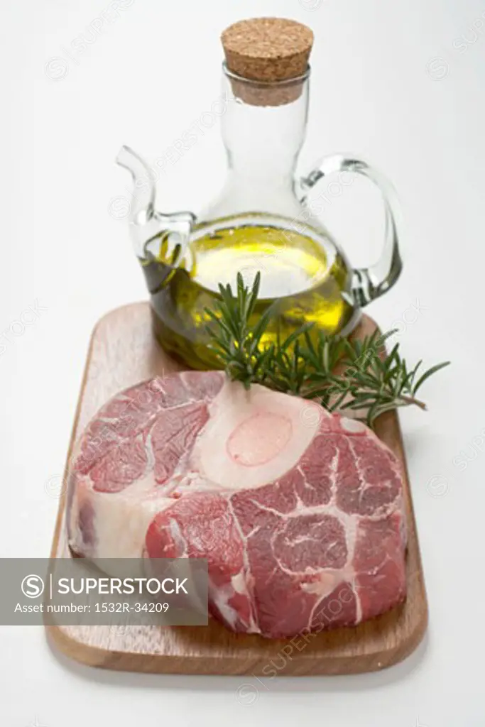 Slice of beef from the leg on chopping board, rosemary, olive oil