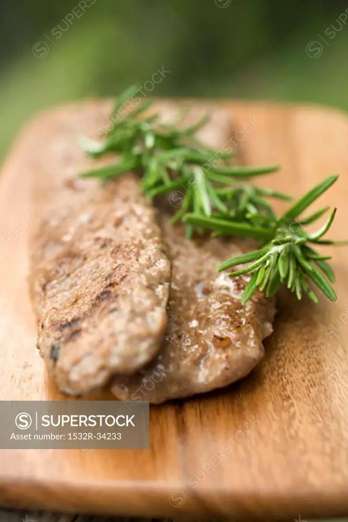 Fried pork sausagemeat with rosemary on chopping board