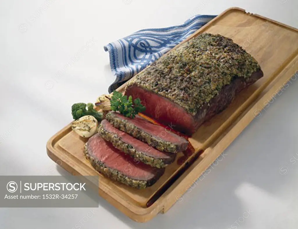 Roast beef with herb crust on chopping board