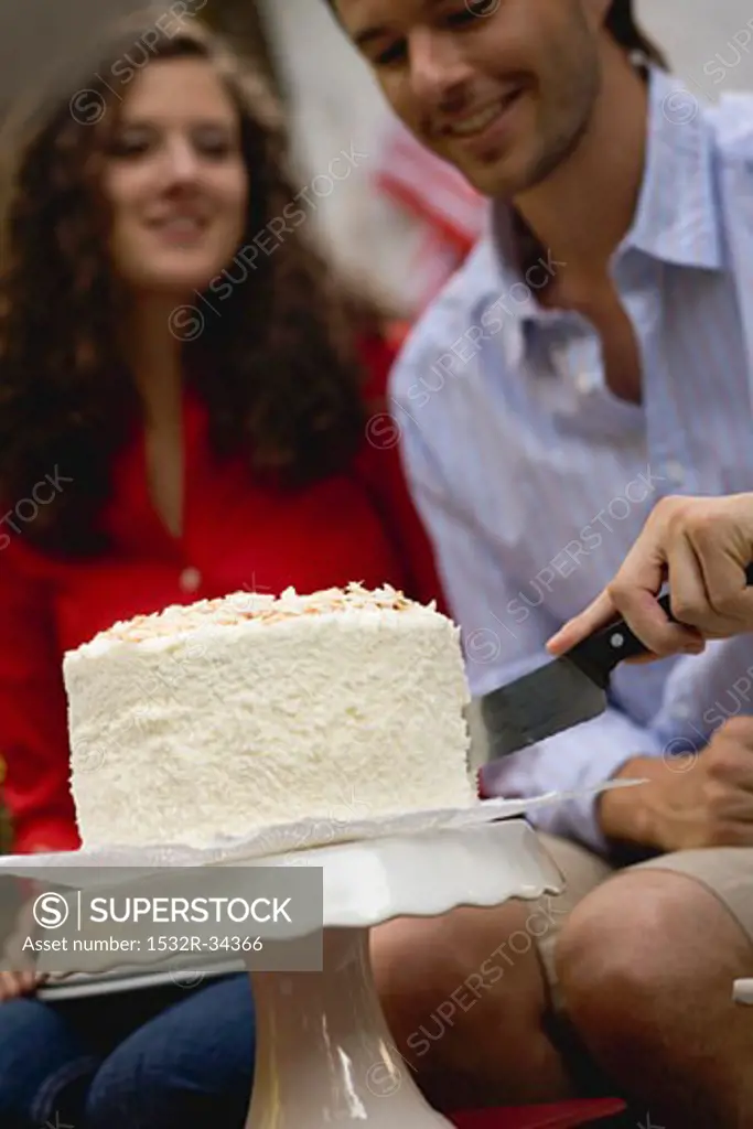 Man cutting coconut cake (4th of July, USA)