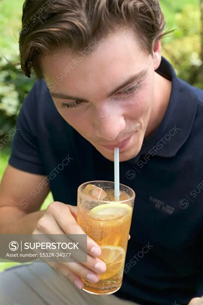 Young man drinking iced tea through a straw