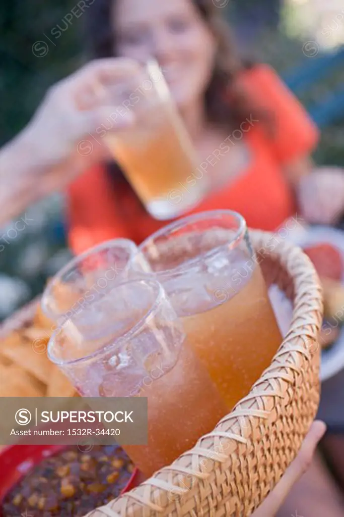 Person serving a basket of iced tea and snacks