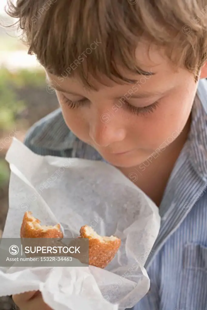 Small boy holding doughnut in paper