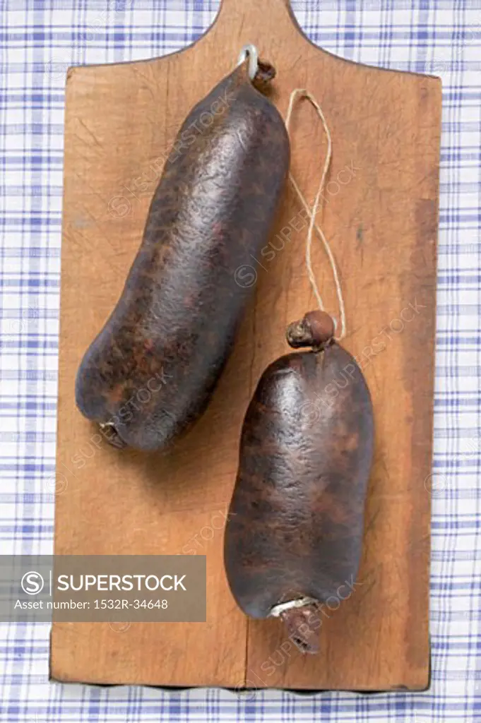 Two black puddings on chopping board (overhead view)