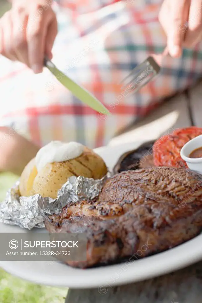 Woman eating grilled steak with baked potato