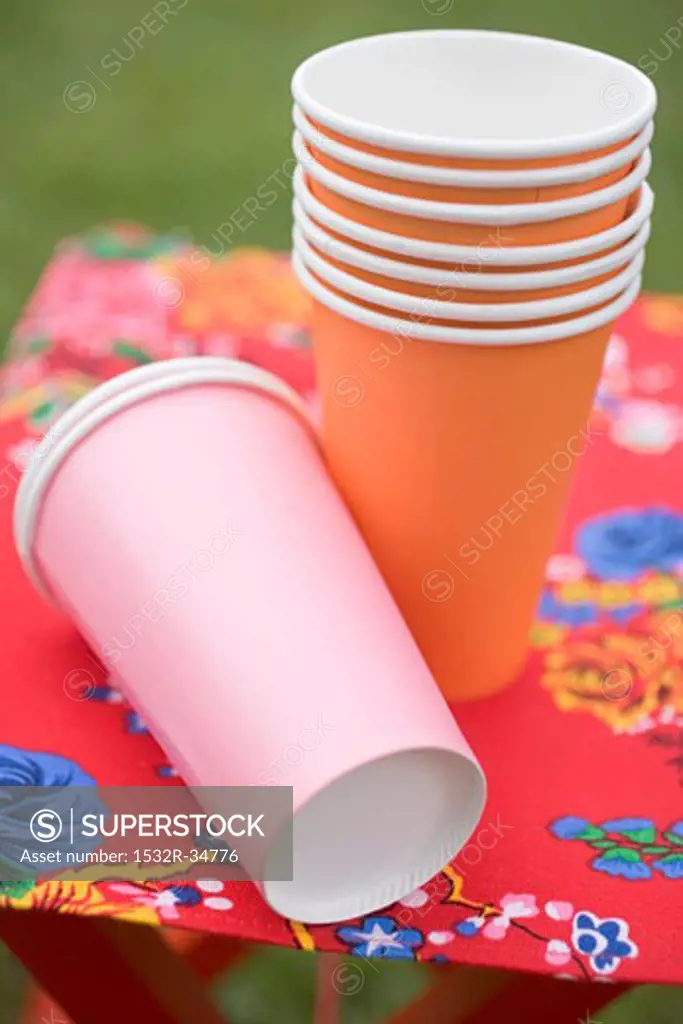 Coloured paper cups on folding stool in garden