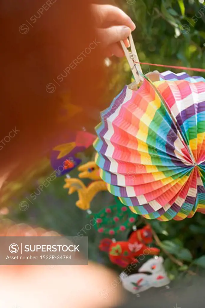Woman hanging coloured Chinese lantern on washing line in garden