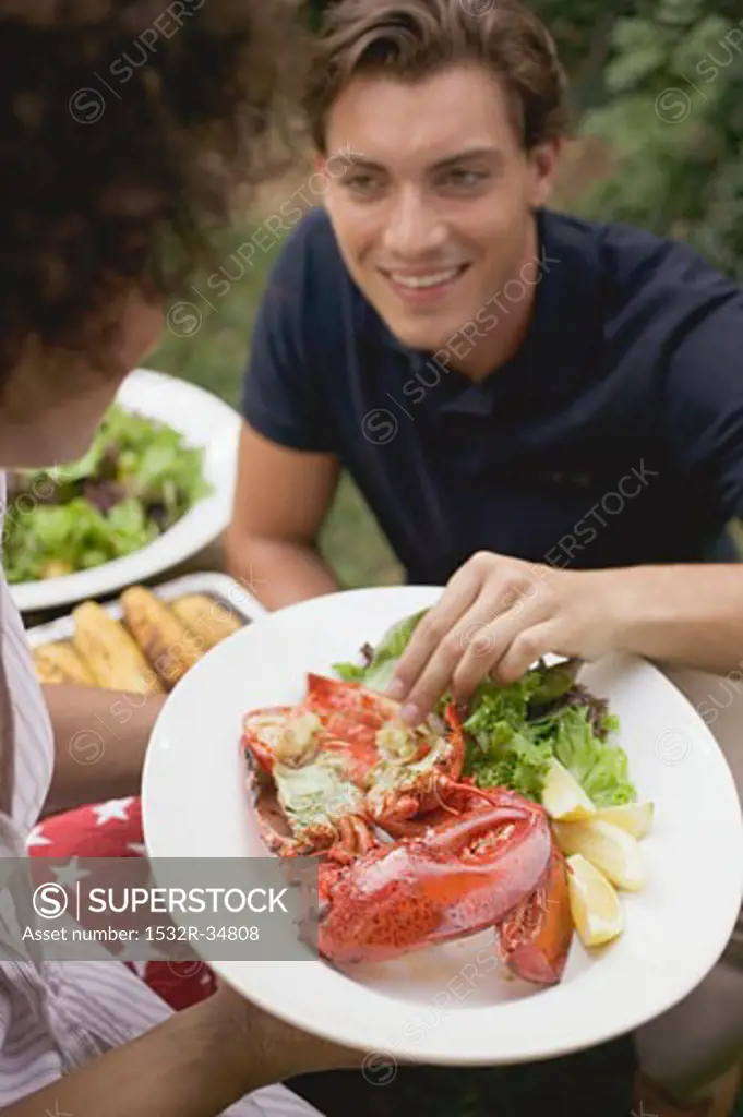 Man taking a piece of lobster from a plate