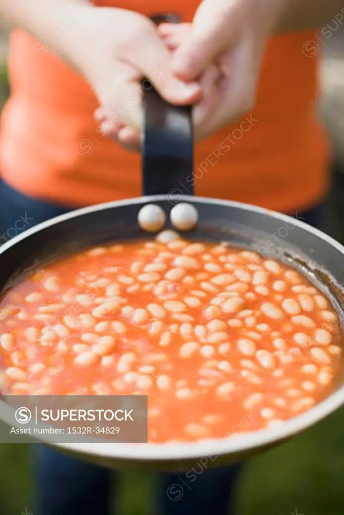 Person holding a pan of baked beans