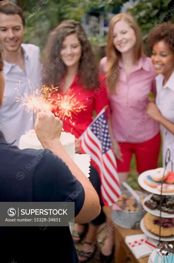 Man serving coconut cake with sparklers (4th of July, USA)