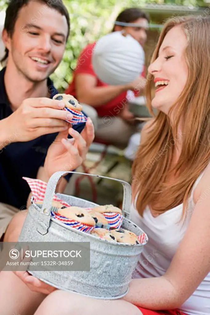 Cheerful couple with blueberry muffins at a garden party
