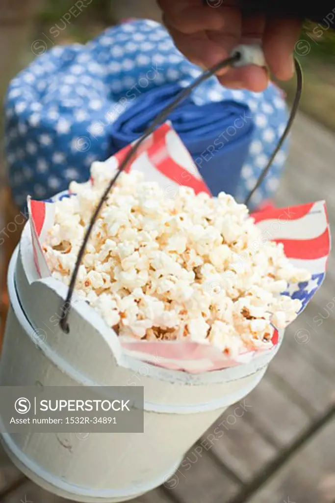 Hand holding wooden bucket full of popcorn (4th of July, USA)