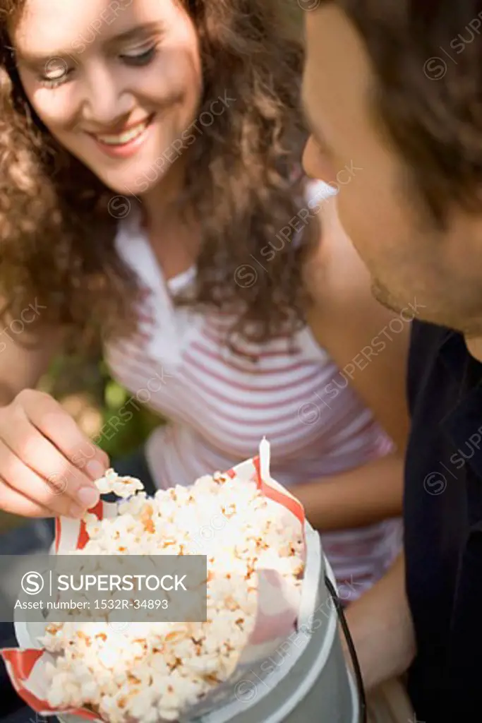 Couple eating popcorn at a picnic