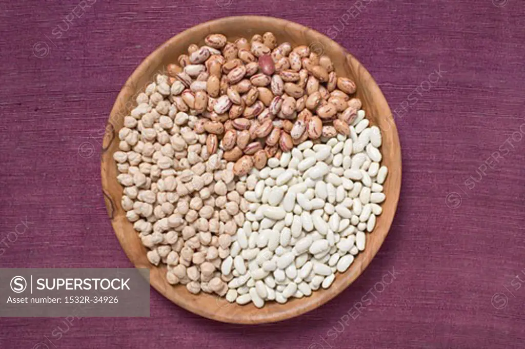 Borlotti beans, white beans and chick-peas in wooden dish