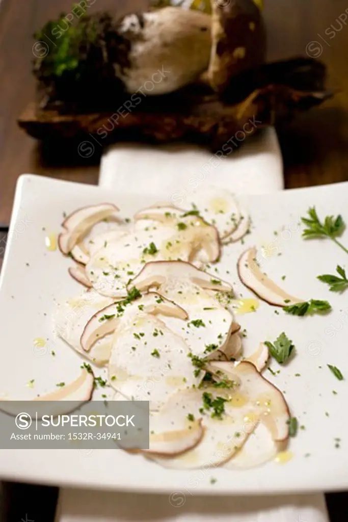 Cep carpaccio on chopping board in front of fresh cep