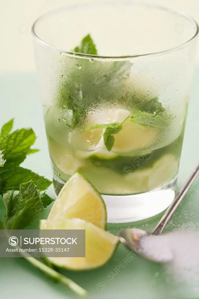 Glass of Mojito with lime & mint, surrounded by ingredients
