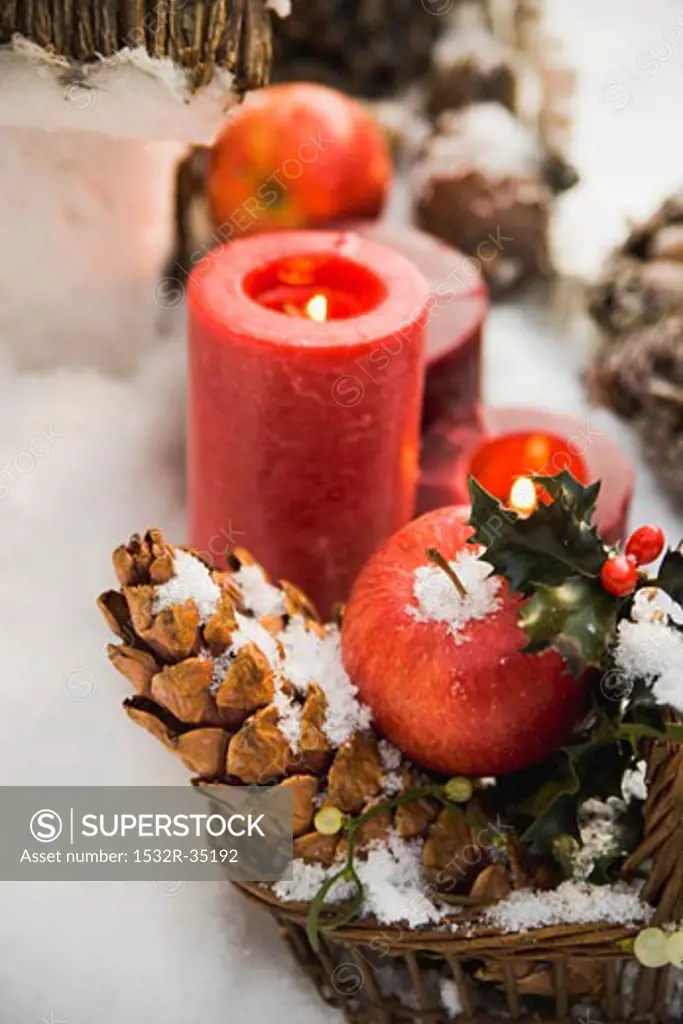 Christmas decorations: apples, cones and candles in snow