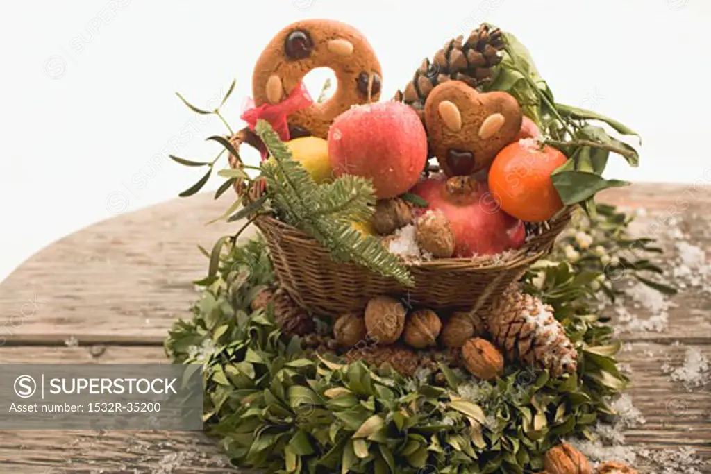 Gingerbread, fruit, nuts and cones in basket on box wreath