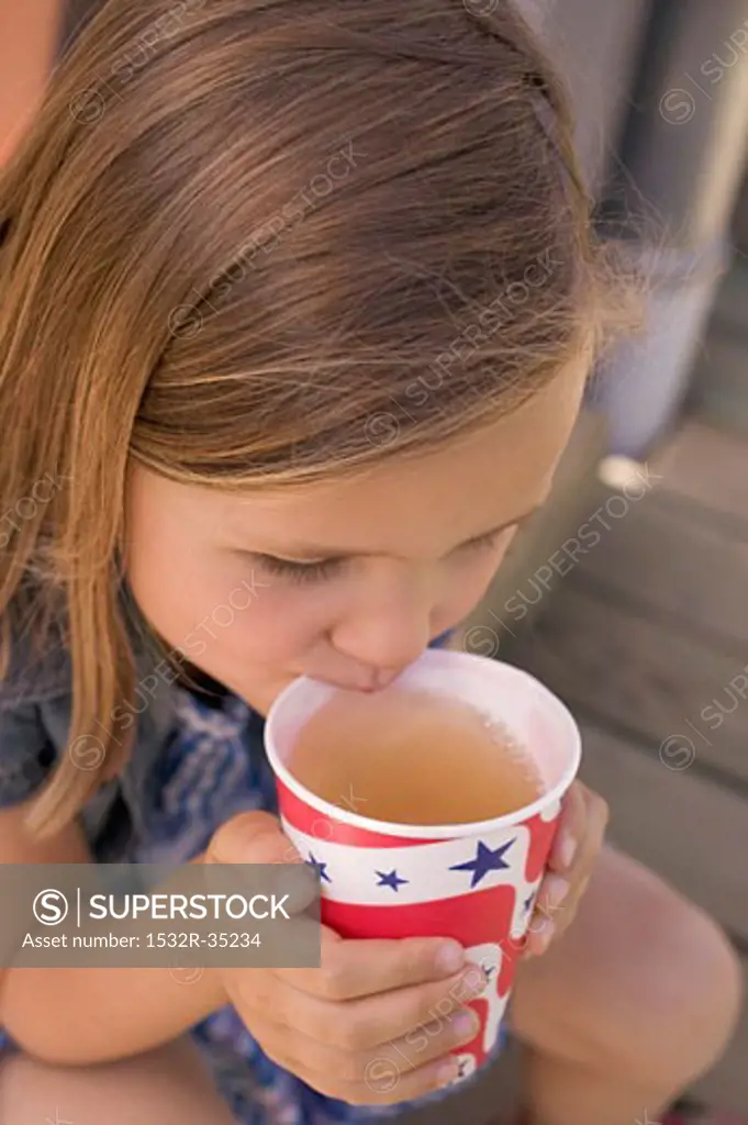 Small girl drinking iced tea out of a paper cup