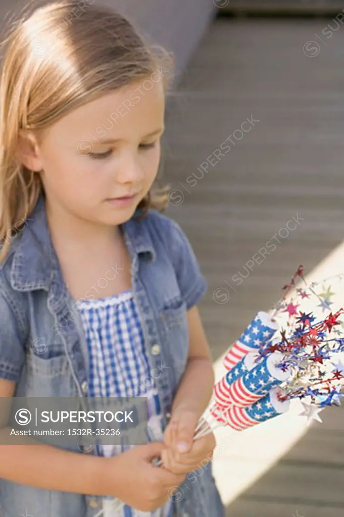 Small girl holding 4th of July decorations (USA)