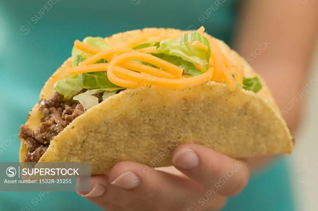 Hand holding a taco filled with mince and cheese