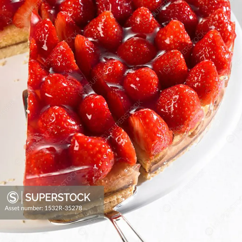 Strawberry flan, partly sliced, with piece on server