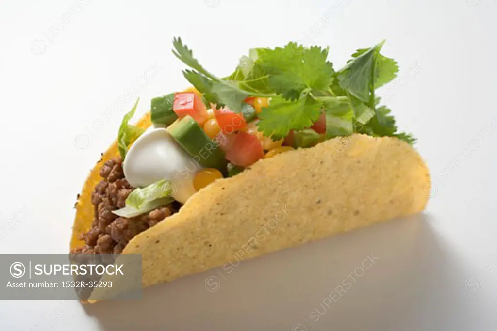 Taco with mince, avocado, sour cream and coriander leaves