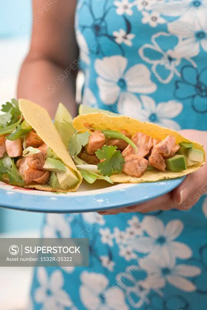 Woman holding plate with two tacos