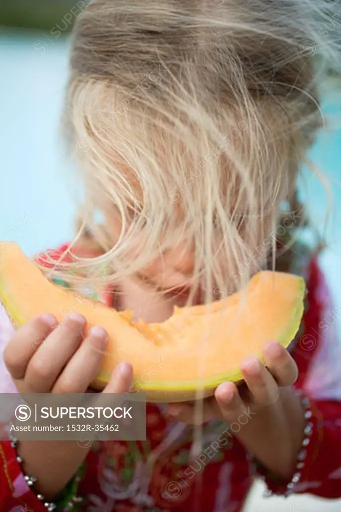 Small girl eating a slice of melon