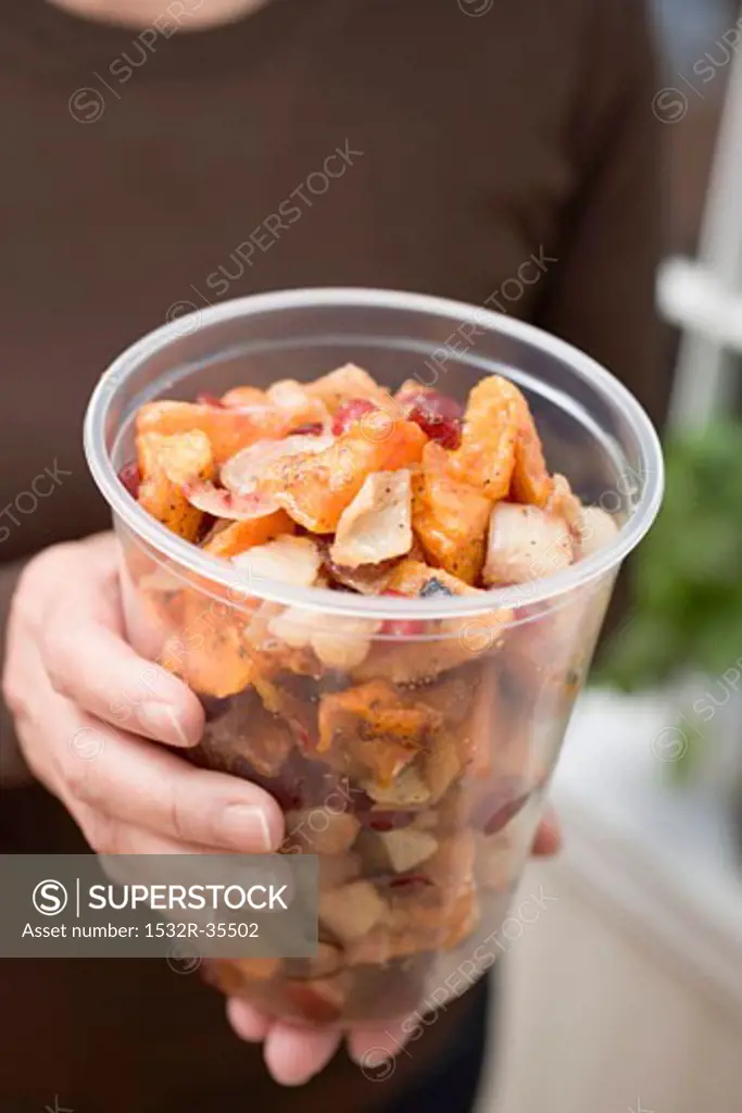 Woman holding vegetable dish in plastic tub
