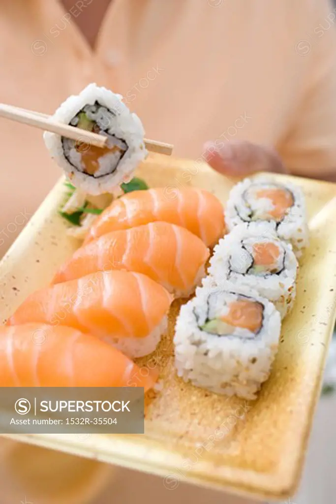 Woman holding sushi on plastic tray