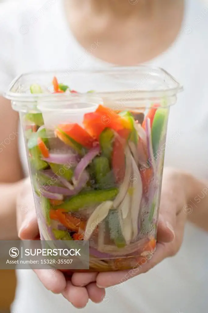 Woman holding plastic container of vegetables