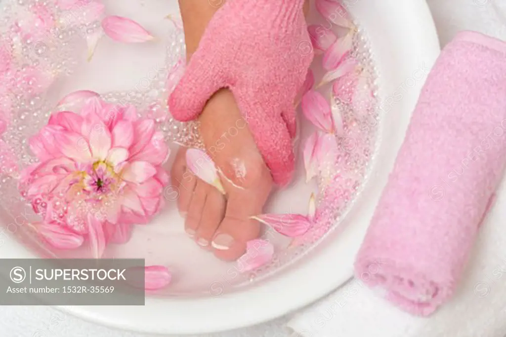Woman washing her foot with pink peeling glove