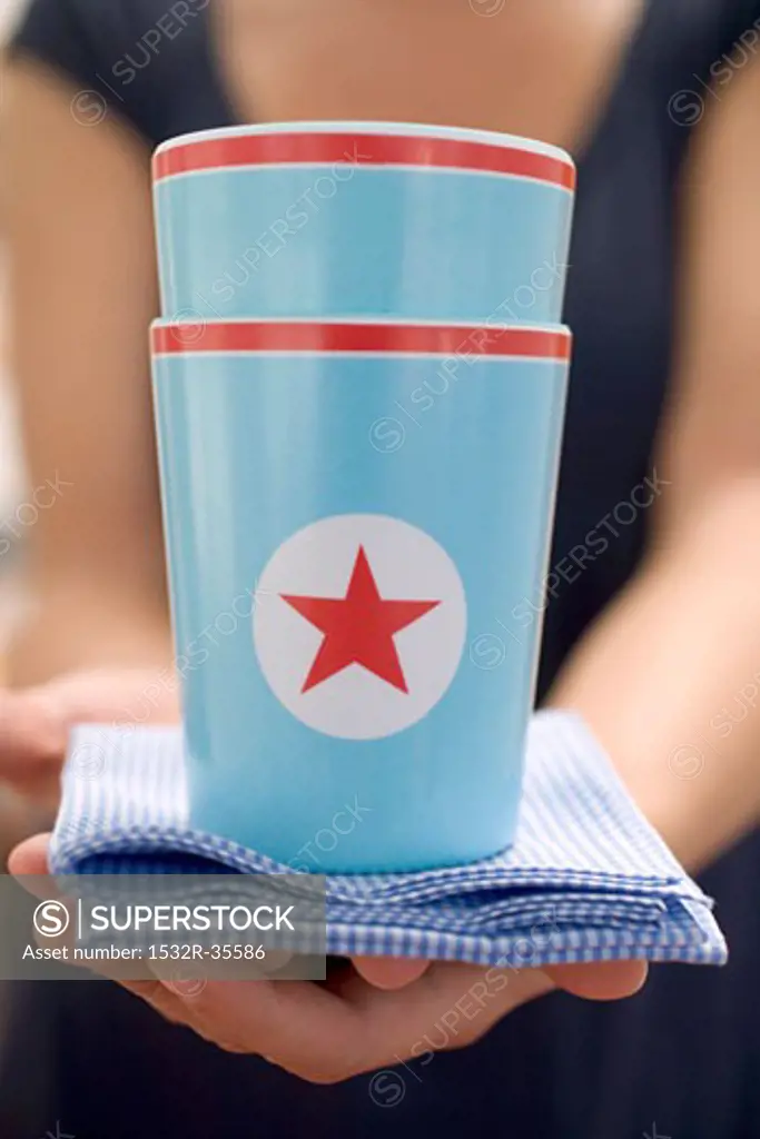 Woman holding two paper cups with stars on checked cloth