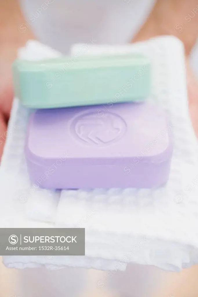 Woman holding two bars of soap on towel