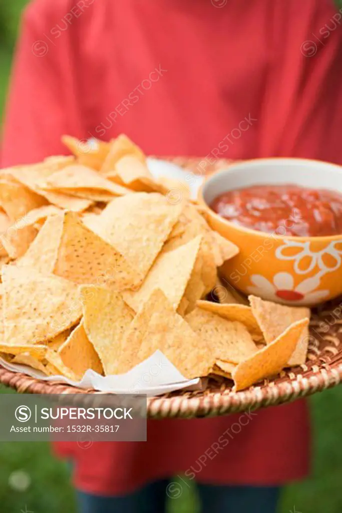 Person holding tray of nachos and salsa