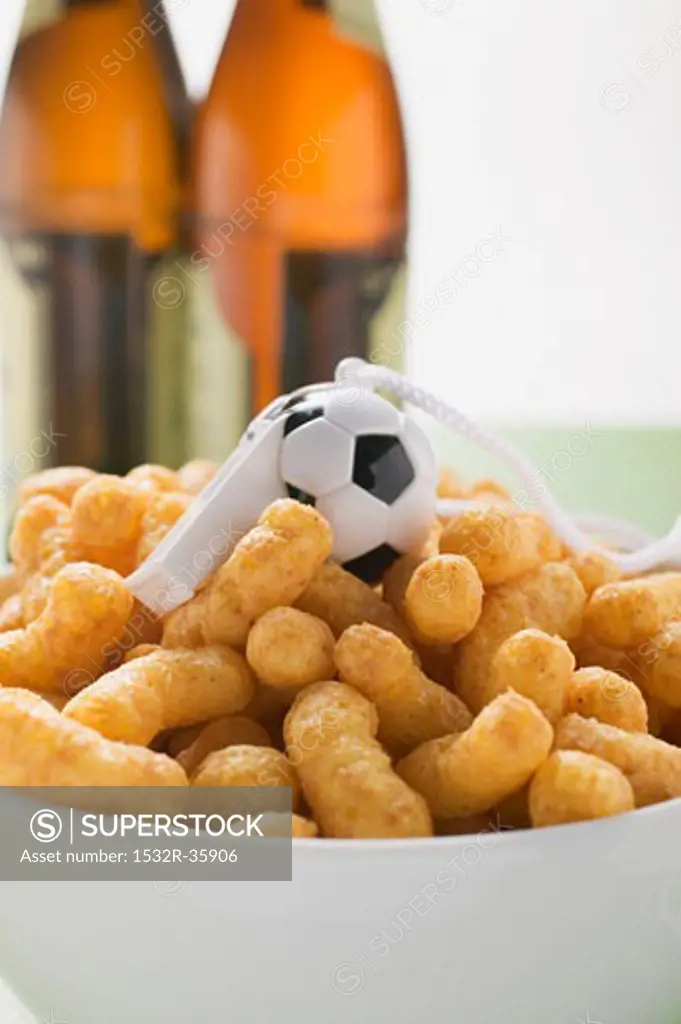 Peanut puffs with whistle in bowl in front of bottles of beer