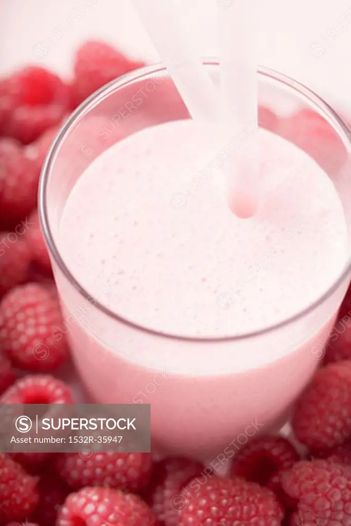 Raspberry shake in glass, surrounded by fresh raspberries