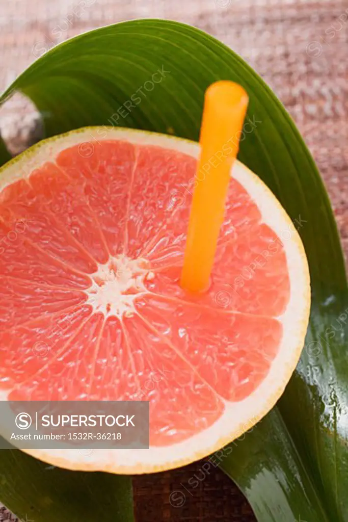 Half a pink grapefruit with a straw