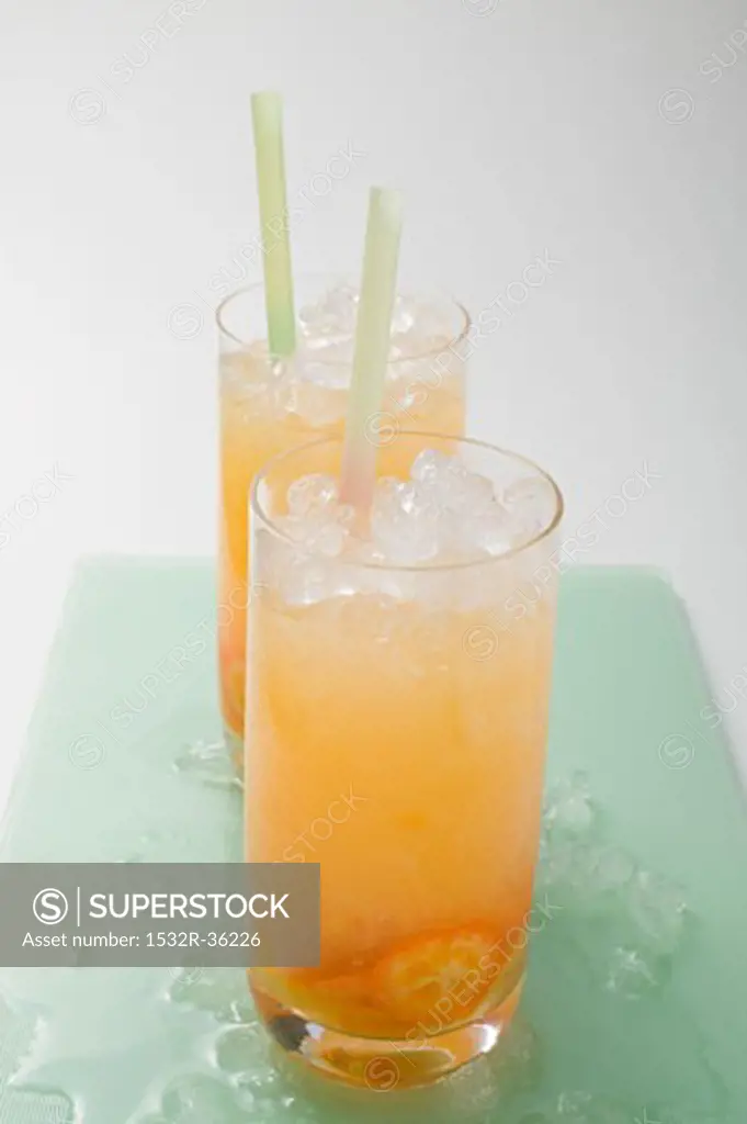 Two fruity drinks with kumquats and crushed ice