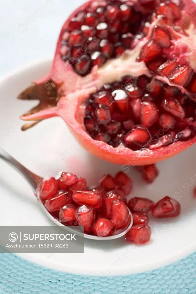 Half a pomegranate and spoonful of pomegranate seeds