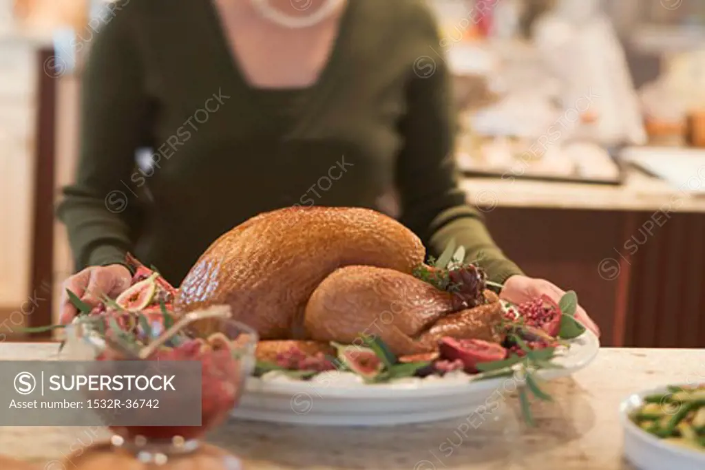 Woman with roast turkey in kitchen (Christmas)